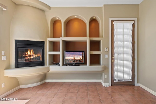 unfurnished living room featuring light tile patterned flooring, a multi sided fireplace, plenty of natural light, and built in features