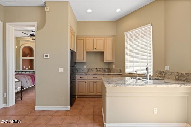 kitchen featuring light brown cabinets, ceiling fan, light stone countertops, light tile patterned floors, and sink