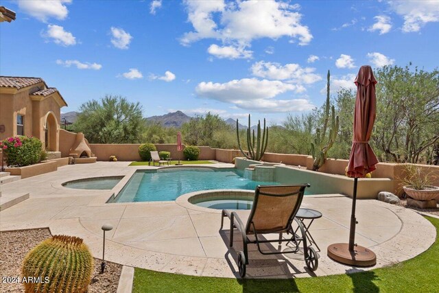 view of pool with an in ground hot tub, a mountain view, and a patio area