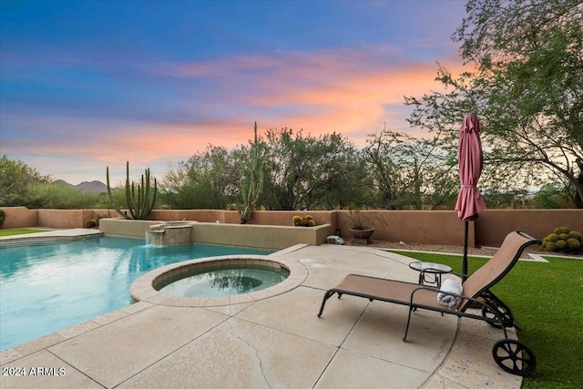 pool at dusk with an in ground hot tub, a patio area, and pool water feature