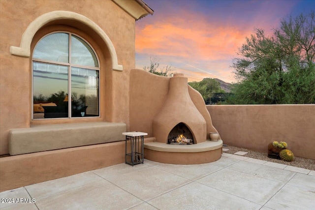 patio terrace at dusk featuring an outdoor fireplace