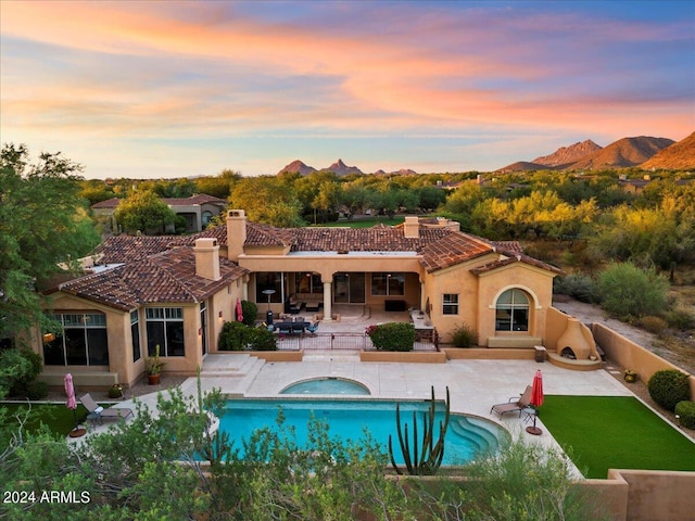 back house at dusk featuring a patio, a mountain view, and a swimming pool with hot tub