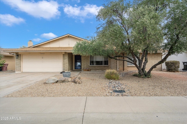 single story home with an attached garage, brick siding, driveway, and a chimney