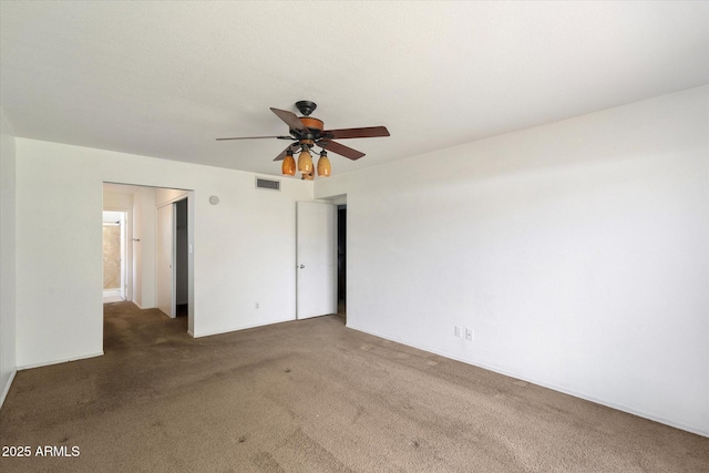 carpeted spare room featuring visible vents and a ceiling fan