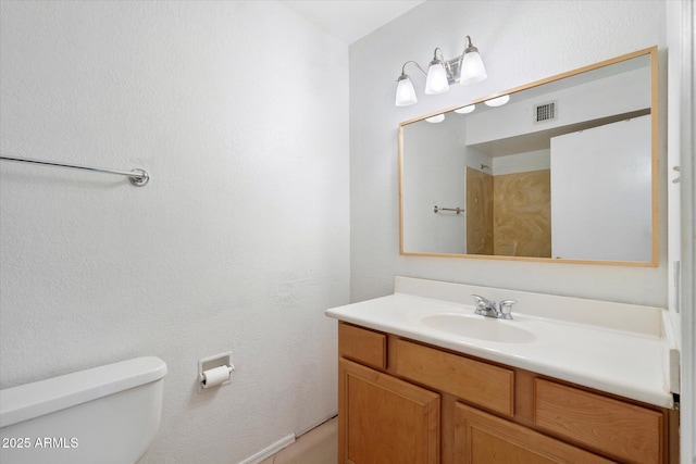 bathroom featuring vanity, toilet, and visible vents