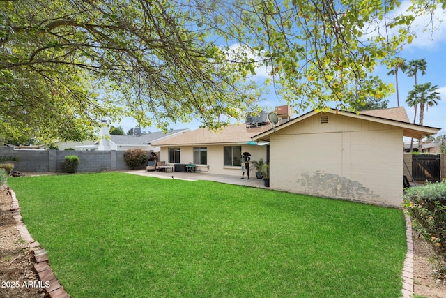 rear view of house with a patio, a lawn, a fenced backyard, and roof with shingles