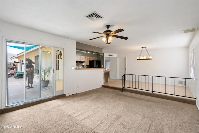 unfurnished room with ceiling fan with notable chandelier, carpet, and visible vents