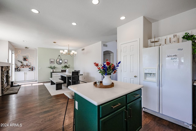 kitchen with white fridge with ice dispenser, a kitchen bar, a center island, green cabinetry, and dark wood-type flooring