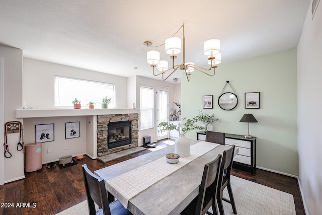 dining area featuring a stone fireplace, dark hardwood / wood-style flooring, and a chandelier