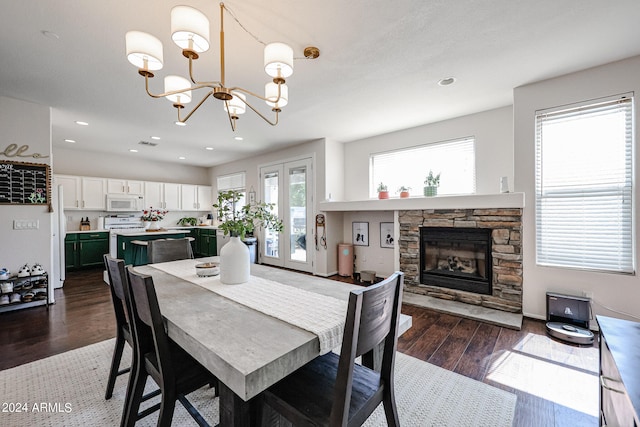 dining room featuring a stone fireplace, a notable chandelier, french doors, and dark hardwood / wood-style flooring