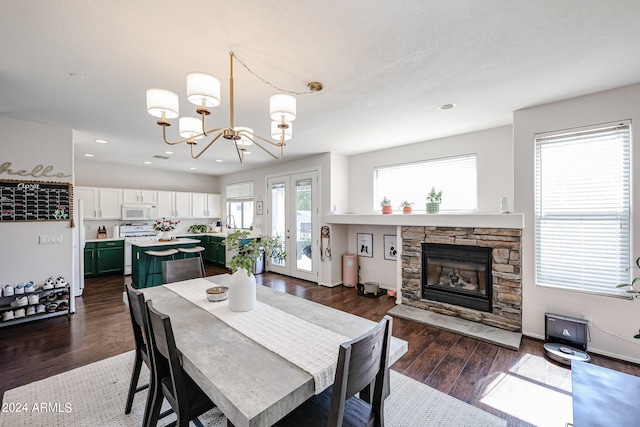 dining room featuring a notable chandelier, sink, a fireplace, and dark hardwood / wood-style flooring