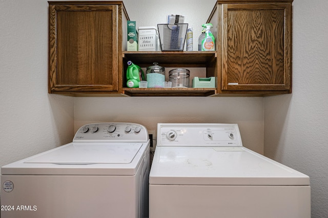 clothes washing area with cabinets and washer and clothes dryer