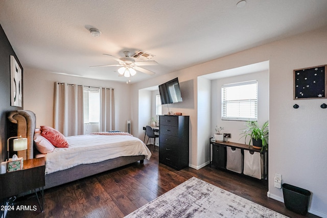 bedroom with dark hardwood / wood-style flooring, ceiling fan, and multiple windows