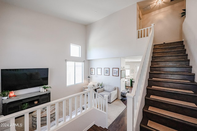 staircase featuring a towering ceiling and hardwood / wood-style flooring