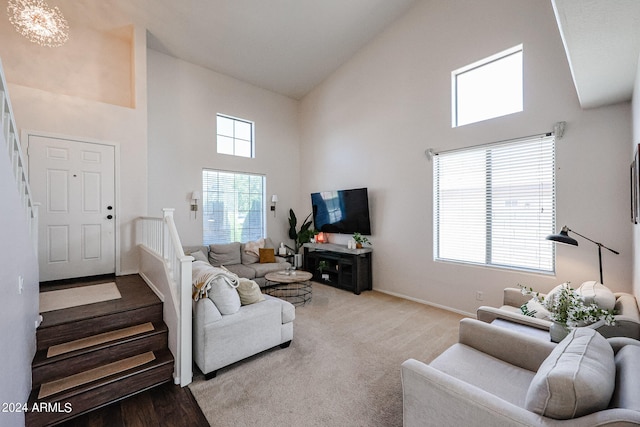 carpeted living room with high vaulted ceiling and an inviting chandelier