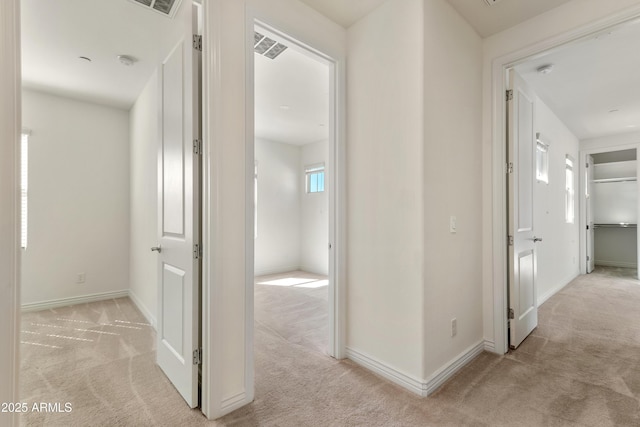 hallway featuring light carpet and baseboards