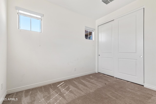 unfurnished bedroom with a closet, visible vents, baseboards, and carpet