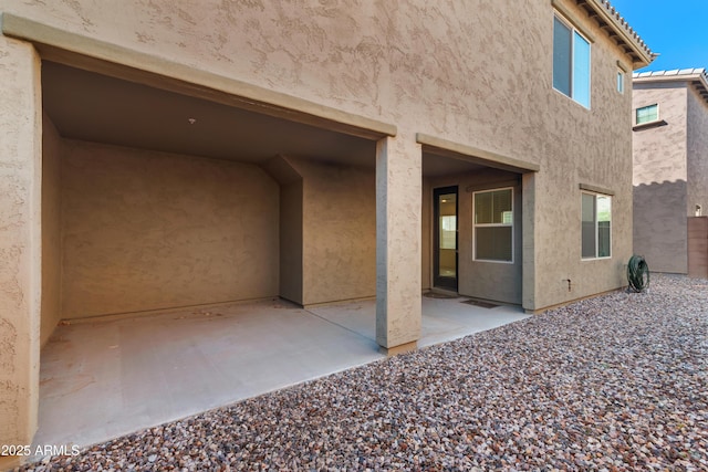 rear view of property featuring stucco siding and a patio