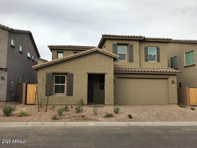 mediterranean / spanish house featuring stucco siding, decorative driveway, an attached garage, and fence