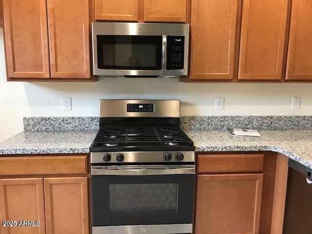 kitchen featuring light stone countertops, brown cabinets, and stainless steel appliances