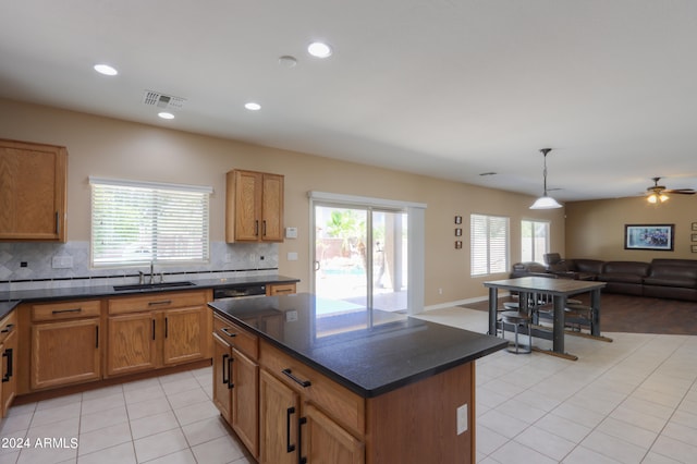 kitchen featuring decorative backsplash, light tile patterned flooring, a kitchen island, ceiling fan, and sink