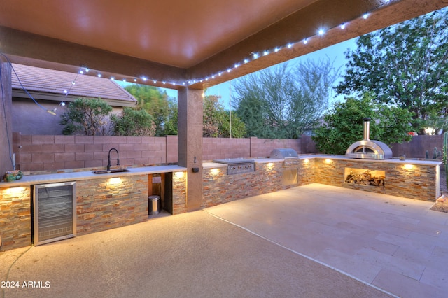 patio terrace at dusk with grilling area, area for grilling, beverage cooler, and sink