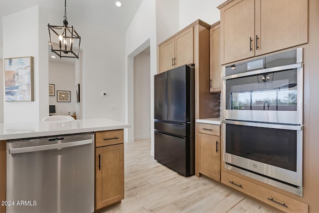 kitchen featuring stainless steel appliances, light hardwood / wood-style flooring, pendant lighting, a chandelier, and light brown cabinetry