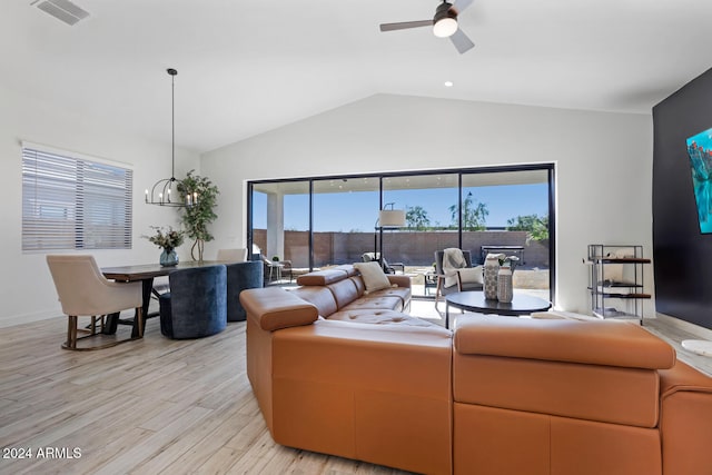 living room with ceiling fan with notable chandelier, vaulted ceiling, and light hardwood / wood-style flooring