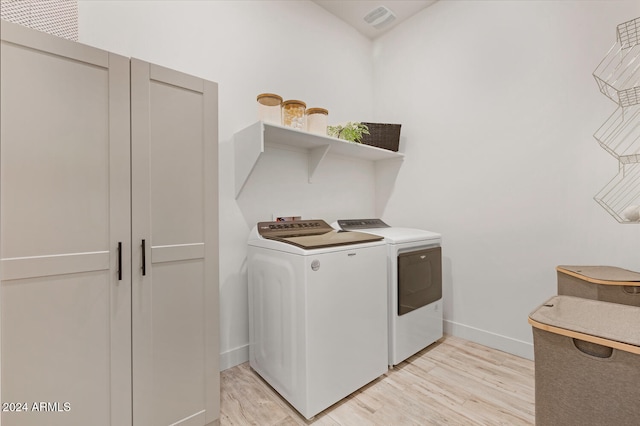 laundry area featuring separate washer and dryer and light hardwood / wood-style flooring