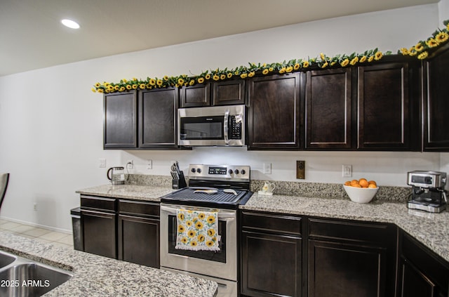 kitchen featuring appliances with stainless steel finishes, light tile patterned floors, and dark brown cabinetry