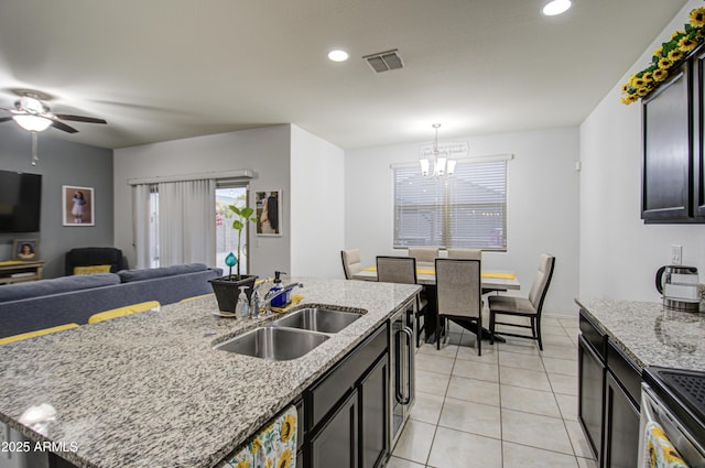 kitchen with sink, light stone countertops, an island with sink, and light tile patterned flooring