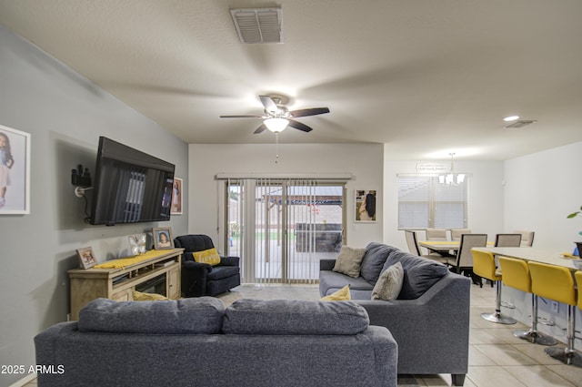 living room featuring light tile patterned flooring and ceiling fan with notable chandelier