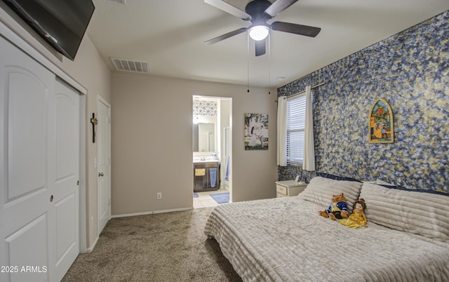 carpeted bedroom with ensuite bathroom and ceiling fan