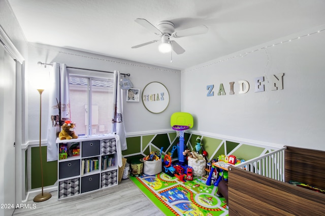 interior space featuring hardwood / wood-style flooring, a crib, and ceiling fan