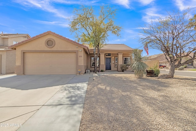 view of front of house with a garage, a tiled roof, concrete driveway, and stucco siding