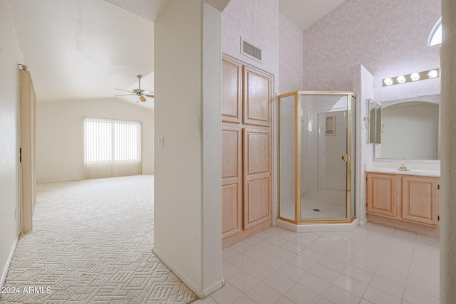 bathroom with vanity, a shower with door, vaulted ceiling, ceiling fan, and a textured ceiling