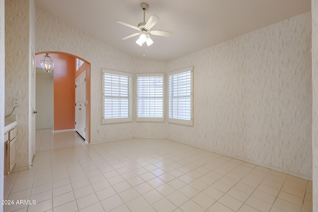 empty room with ceiling fan with notable chandelier and light tile patterned flooring