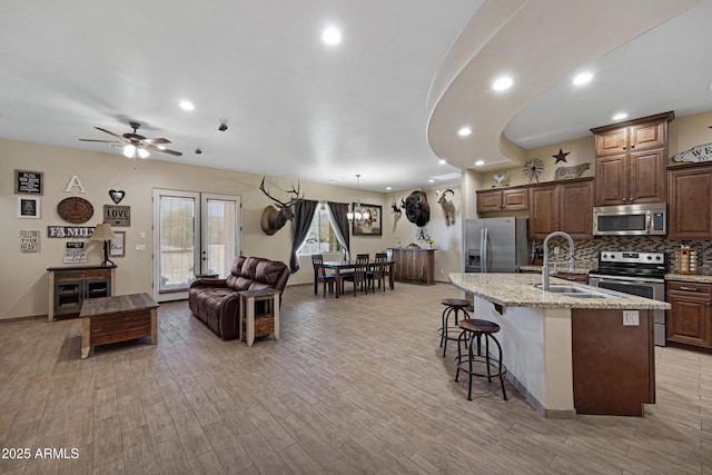 1008 E Mano Dr, New River, AZ 85087 - kitchen featuring stainless steel appliances, a sink, a kitchen island with sink, a breakfast bar, and light wood-type flooring