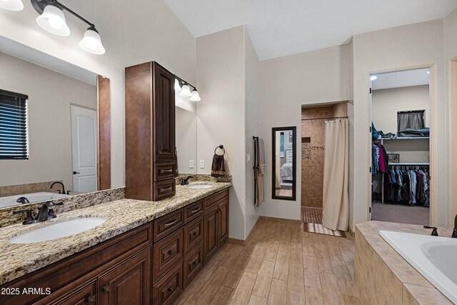 1008 E Mano Dr, New River, AZ 85087 - bathroom featuring tiled shower, a bath, double vanity, and wood finished floors
