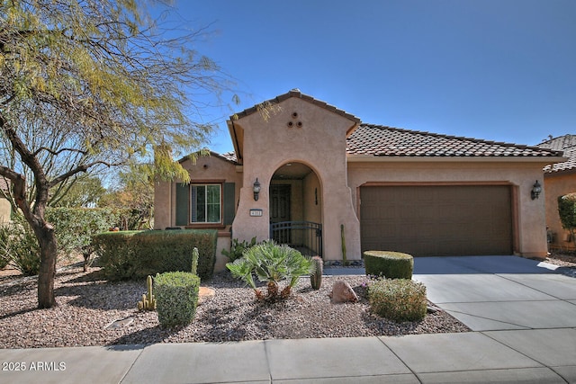 mediterranean / spanish house with concrete driveway, a tiled roof, an attached garage, and stucco siding