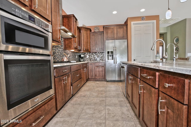 kitchen with light tile patterned flooring, a sink, hanging light fixtures, appliances with stainless steel finishes, and decorative backsplash