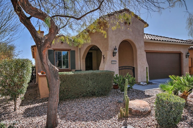 mediterranean / spanish home featuring a garage, a gate, a tile roof, and stucco siding