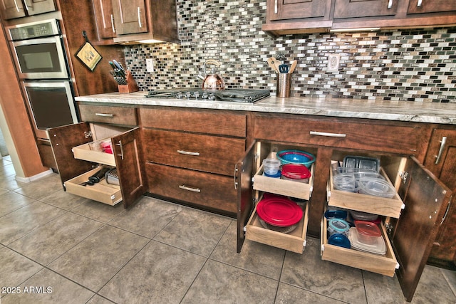 kitchen with dark brown cabinets, stainless steel appliances, decorative backsplash, and tile patterned floors