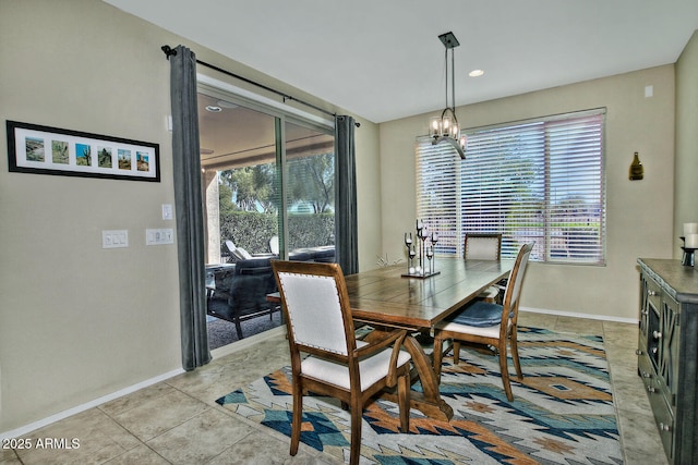 dining area featuring light tile patterned floors, baseboards, and an inviting chandelier