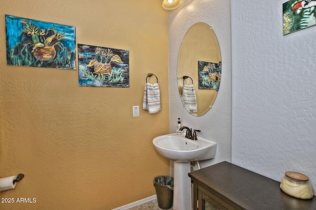 bathroom featuring a textured wall and baseboards