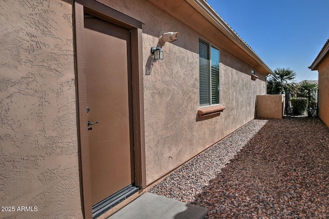 exterior space with a gate and stucco siding