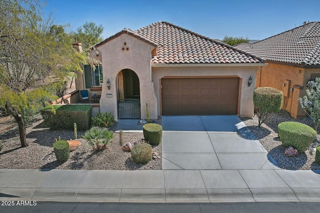 mediterranean / spanish-style home with a garage, concrete driveway, a gate, and stucco siding