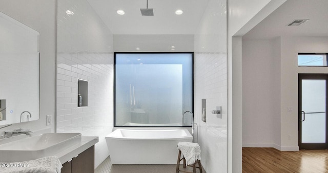 full bath featuring visible vents, a freestanding bath, recessed lighting, wood finished floors, and vanity