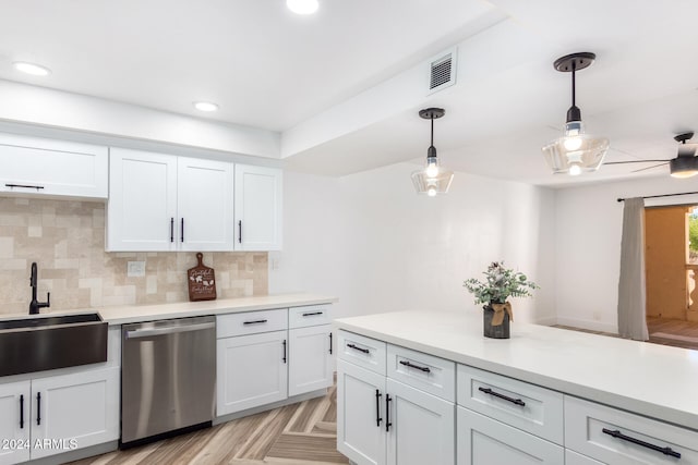 kitchen featuring stainless steel dishwasher, white cabinets, hanging light fixtures, and tasteful backsplash