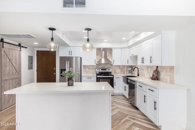 kitchen with decorative light fixtures, stainless steel appliances, white cabinetry, and wall chimney exhaust hood